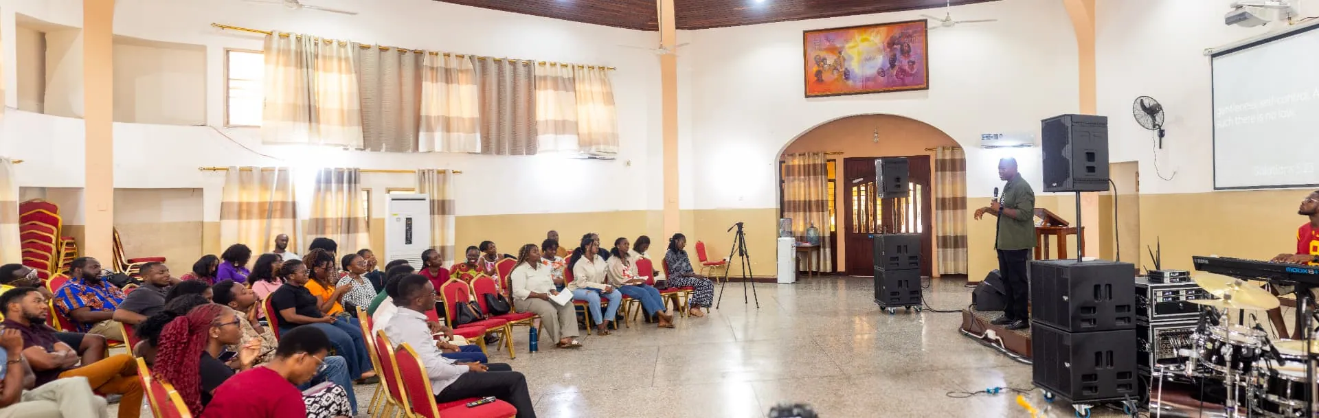 A wide view of a Faith Camp teaching session, the speaker at the front and the room listening