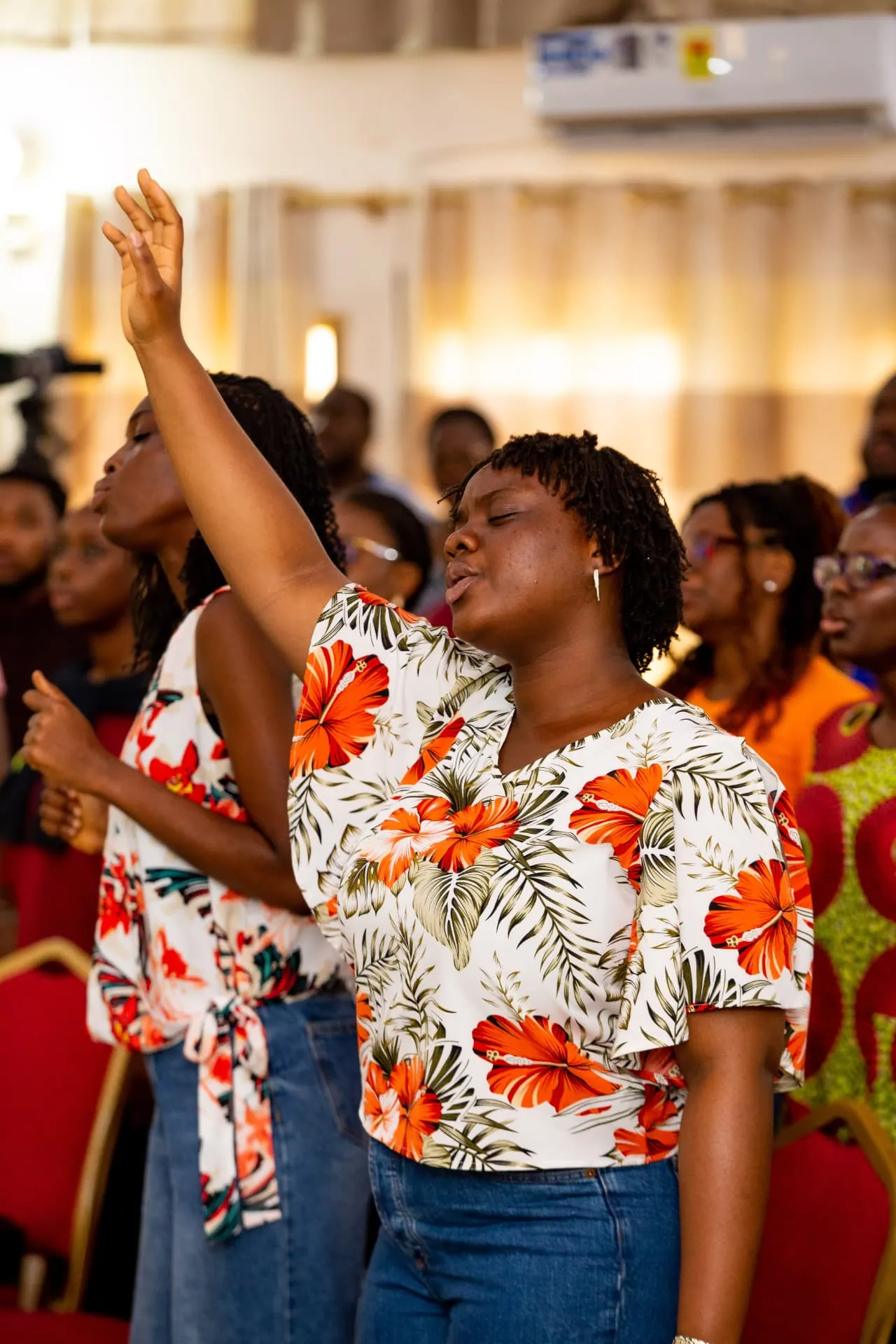 A woman worshipping with her hand raised during a Faith Camp session