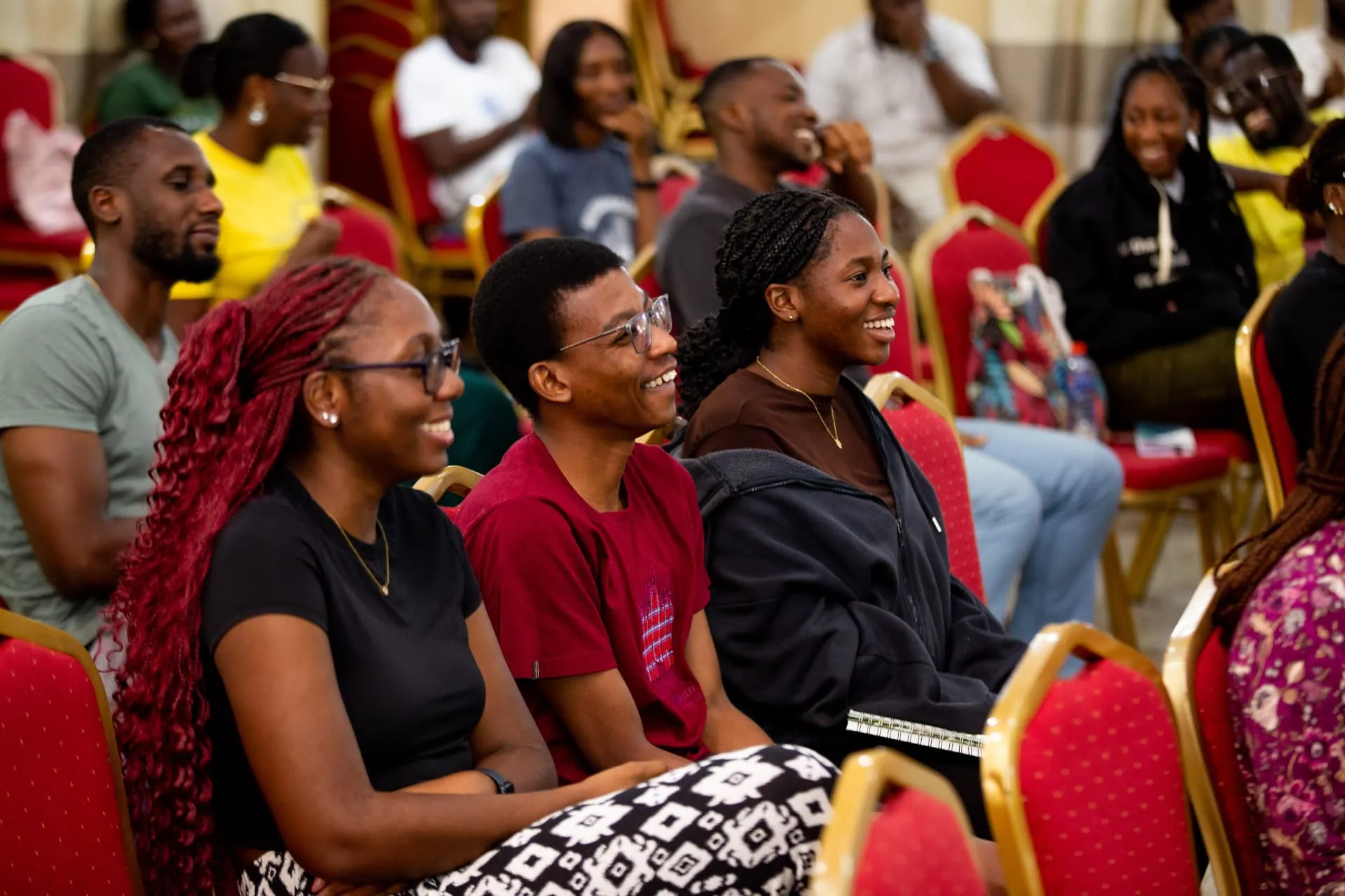 Three friends smiling as they listen during a teaching session